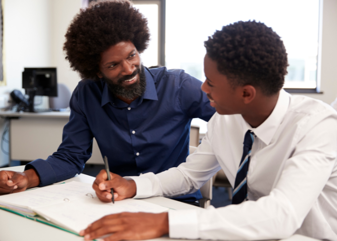 Black male teacher teaching black male student